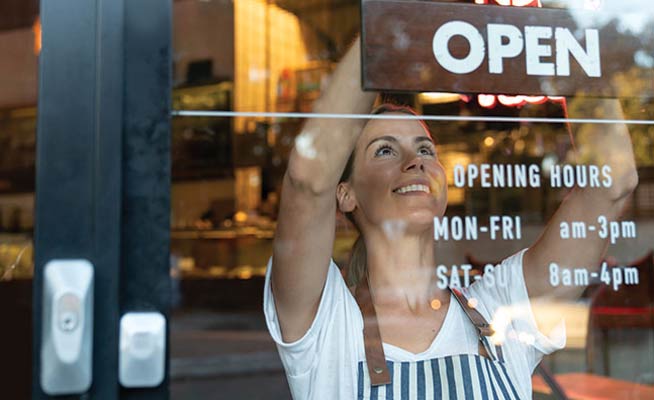 Business person hanging their open sign in the window.